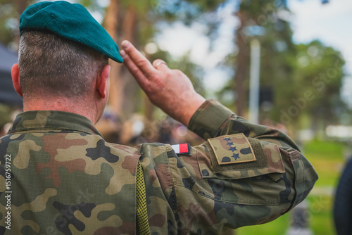 A Polish soldier saluting and seen from behind.