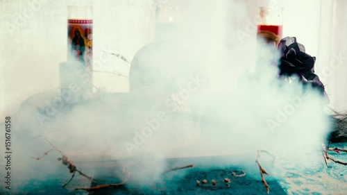 Voodoo related objects on a table including a skull, a knife and candles. Smoke in reverse quickly and mysteriously exits left.