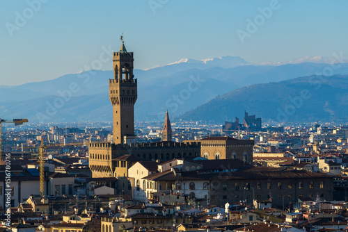 Panoramic view of Florence with Palazzo Vecchio and Torre di Arnolfo, Tuscany, Italy, framed by rooftops and snowy Apennine mountains.