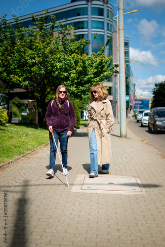 Visually impaired woman walking with her female friend in the city
