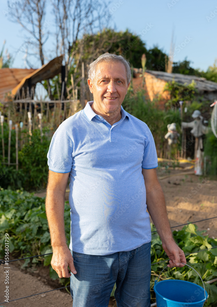 Fototapeta premium Portrait of elderly positive man on his farm on a summer day