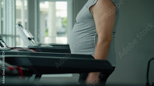 middle-aged fat man is running on a treadmill in a gym to lose weight and be healthy.	
