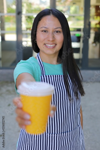 Beautiful female barista holding a to go coffee cup 