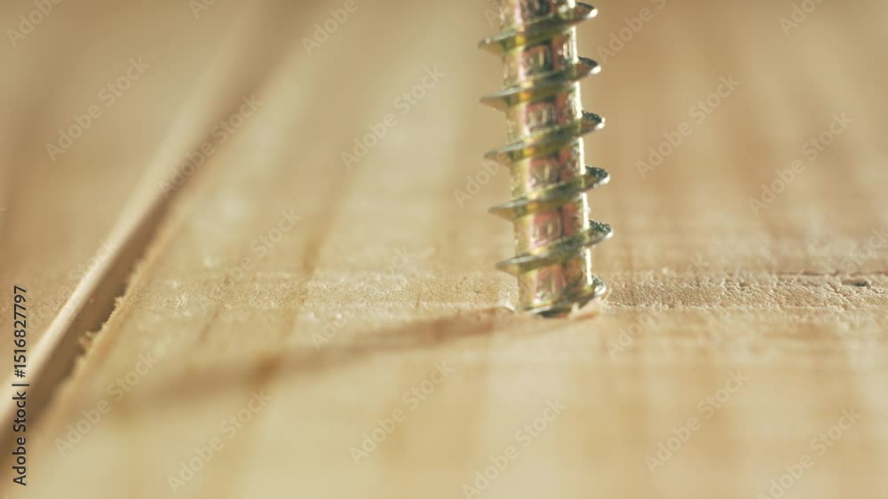 Close-up yellow self tapping screw screwing into wood by man using hands. Macro view construction fastener turning manually without tool by repairman. Metal screw working into board by builder with