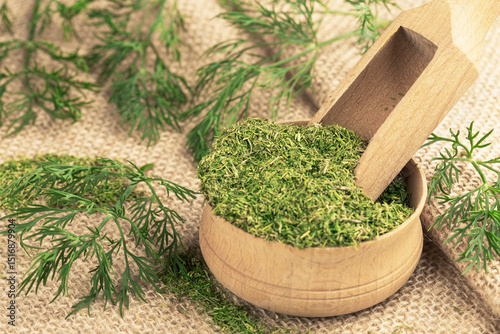 Dried chopped dill in a wooden bowl and sprigs of fresh dill