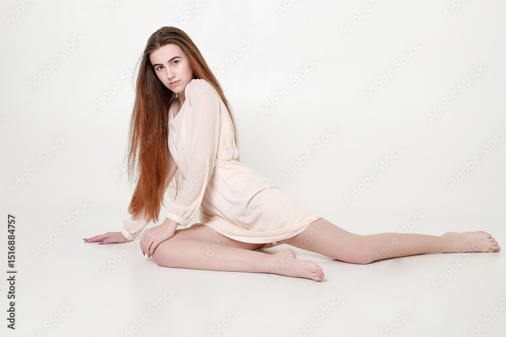 Beautiful tender young girl in a white long dress and with long hair sits Beautiful tender young girl in a white long dress and with long hair sits