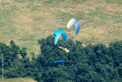 Sestola, Italy – 05 31 2025: Paraglider flies in the air. Aerial view of paragliding. Paraglider flies above the mountains in a bright sunny day. Concept of extreme sport.
