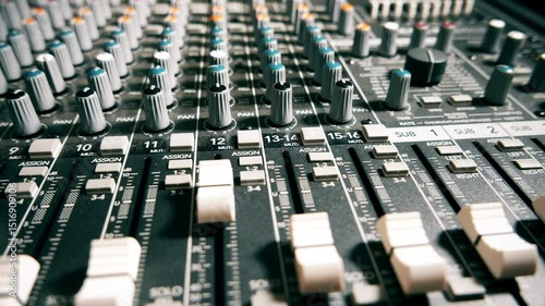 Pro audio mixing board faders and knobs.  Slider shot of multi-track music recording equipment.