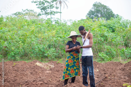 two african farmer working on a farm happily using cellphone