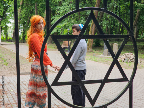 mother and son jews at jewish cemetery pay homage to ancestors, jewish woman in wig and long skirt, boy in kippah