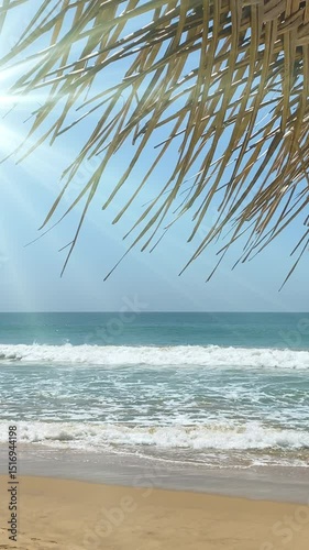 Bright sun shines over a peaceful beach with soft waves lapping the shore. A straw beach umbrella adds shade and tropical charm. Perfect summer vacation and relaxation atmosphere
