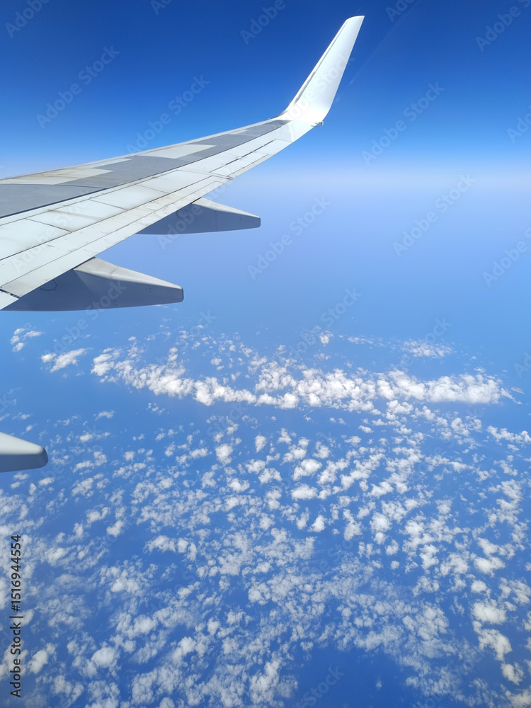 Fototapeta premium Coastal aerial view from airplane window flying above deep blue sea