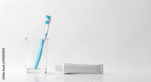 Toothbrush in glass and toothpaste tube on white background