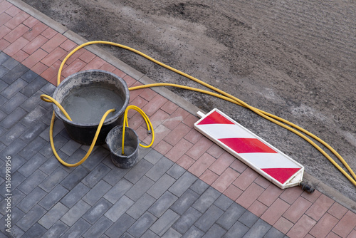 Gelber Wasserschlauch und Eimer auf einer Baustelle