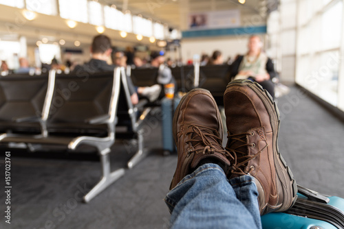 Traveler Relaxing At Airport With Feet On Suitcase
