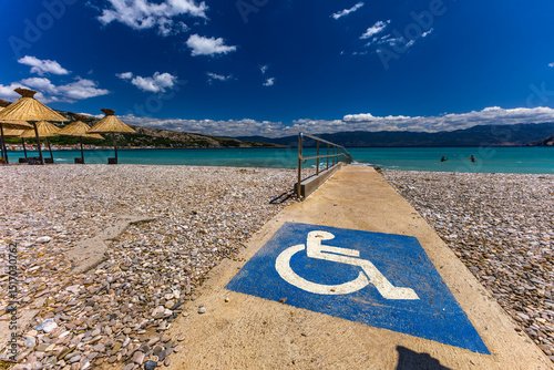 Fototapeta Naklejka Na Ścianę i Meble -  Sunshades on the beach of Baska on the island of KRK, preparation for the tourist season in Croatia