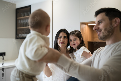 Happy family holding baby and smiling in kitchen