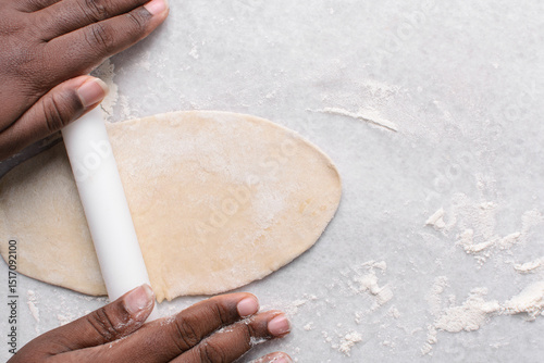 Overhead view of paratha dough being rolled out, top view of flaky flatbread dough, process of making paratha	