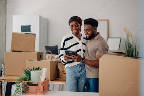 Tableau sur toile Happy couple admiring photo in new home surrounded by moving boxes