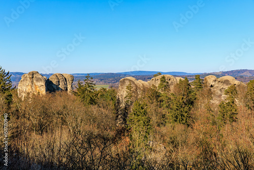 Rock formations and forest landscape under clear blue sky in mountainous region