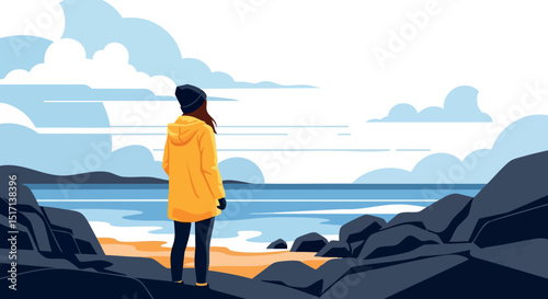 Woman in yellow jacket standing on rocky coast looking at ocean under cloudy sky 