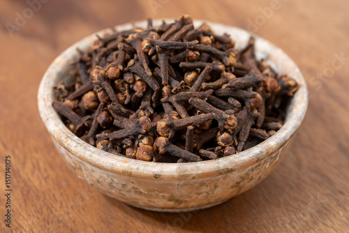 Fototapeta Naklejka Na Ścianę i Meble -  Stone bowl with dried clove buds, used for cooking and traditional medicine, close-up, spices collection
