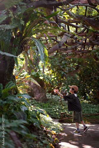 Asian little boy sitting in the garden and touching the sunlight photo