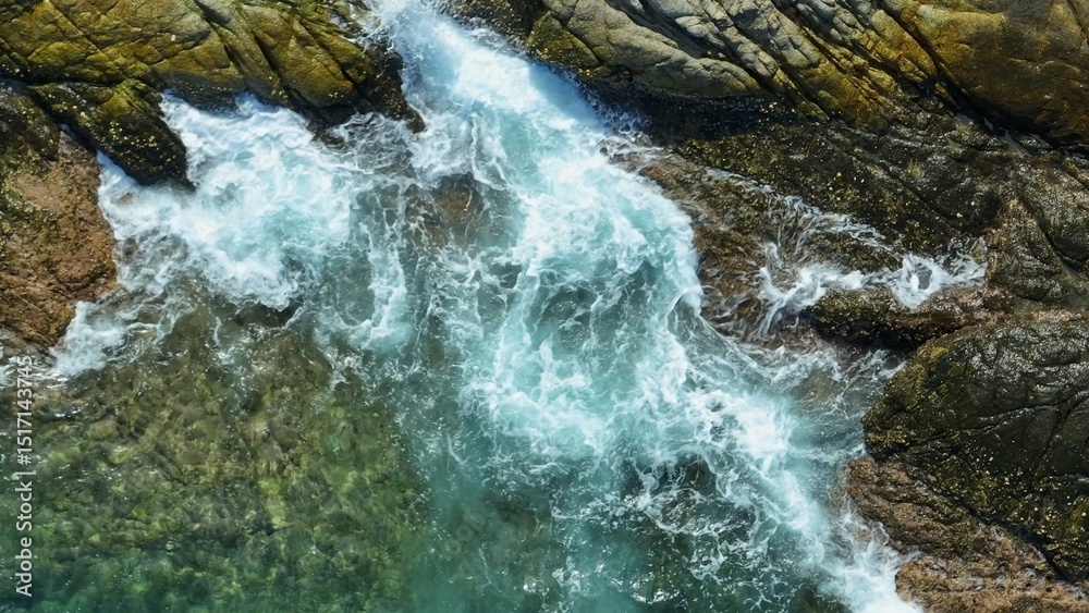 Naklejka premium The aerial shot captures the epic crash of waves, slowing down the intense impact as water explodes against the rugged coastline, revealing the ocean’s vast, relentless energy. 