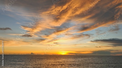 A stunning aerial view of the tropical sea at sunset, where golden light dances on the water's surface, blending seamlessly with the vibrant sky and calm ocean below. Thailand.
