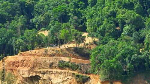 The aerial view reveals the devastation of deforestation, with trees cleared for development, exposing soil and contributing to global warming by releasing carbon and reducing biodiversity.
