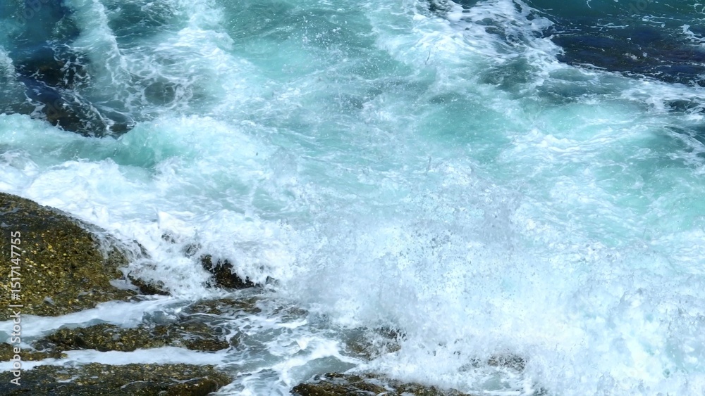 Fototapeta premium A powerful aerial view of waves crashing on rocks, sending spray into the air, capturing the movement and energy of the ocean, perfect for dynamic coastal and nature themes. Phuket, Thailand. 