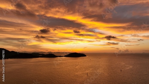 A stunning sunset over the ocean, with vibrant orange and purple hues painting the sky as the sun sets behind the mountains, creating a peaceful and breathtaking coastal landscape. Thailand.
