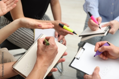 Group of people writing in notebooks during life coaching class indoors, closeup photo