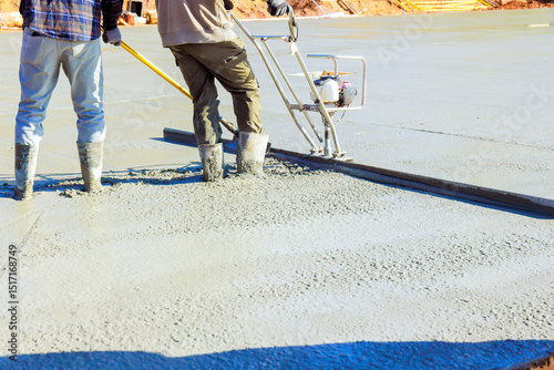 Contractor use screed to level freshly poured concrete on construction site in broad works day