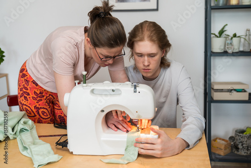 Woman teaching teenager how to use sewing machine