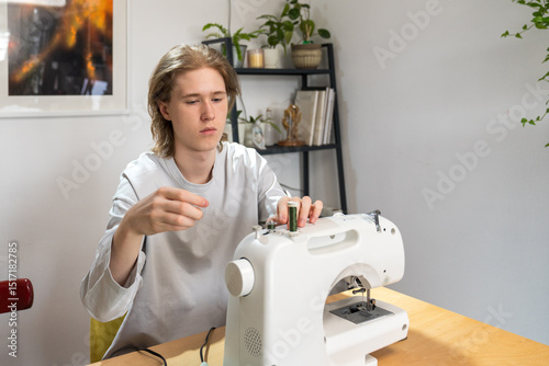 Boy threading sewing machine at home workspace