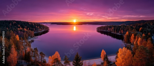 Breathtaking panoramic view of tranquil lake surrounded by vibrant autumn foliage under a colorful sky at sunrise embodying the serene beauty of nature's changing seasons