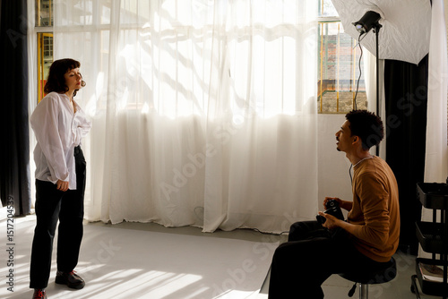 A model poses gracefully, wearing an oversized white shirt. Her eyes a photo