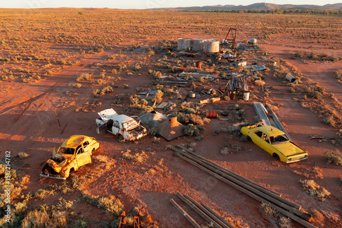 Car wrecks and scrap metal scattered in desert photo