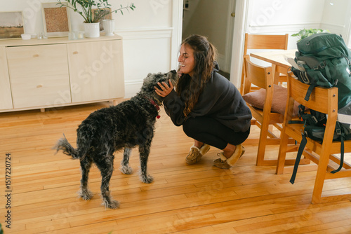 dog welcoming young woman with backpack coming home, 