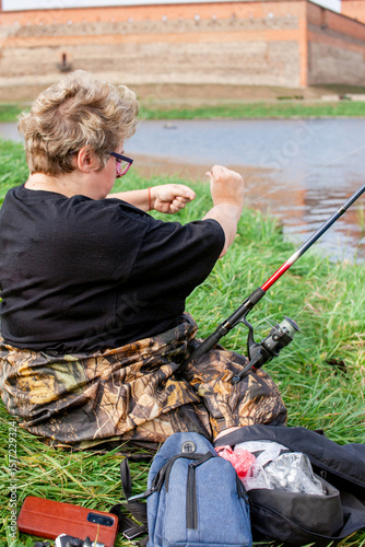A woman on a fishing trip is stringing bait on a hook.