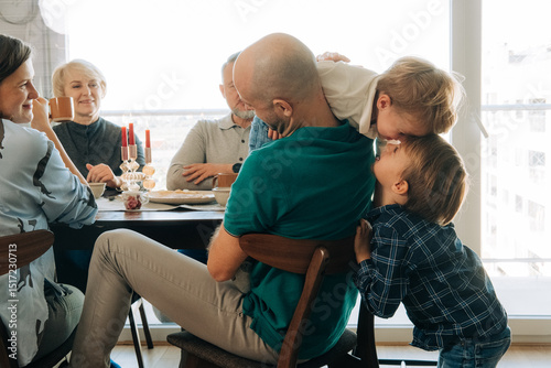 Two siblings playing during festive breakfast with family photo