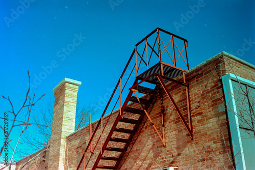 Fire escape and chimney against saturated sky