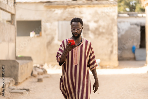 Senegalese man wearing traditional clothes using smartphone in Africa