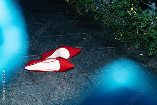 pair of red high heels on the wet pavement