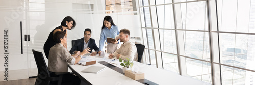 Group of professionals brainstorming gather in modern conference room, panoramic view. Team reviewing documents, exchanging ideas about strategic plan, project updates, or business decisions. Briefing