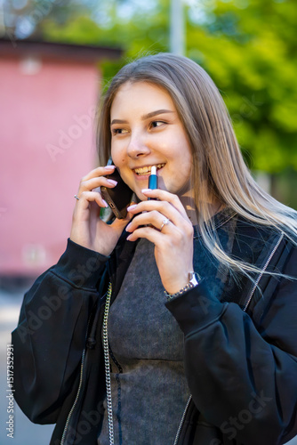 Wallpaper Mural Young woman smoking e-cigarette talking on the phone in the street. Addiction concept. High quality photo.	 Torontodigital.ca