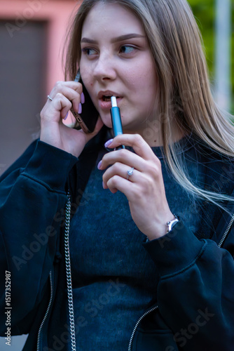 Wallpaper Mural Young woman smoking e-cigarette talking on the phone in the street. Addiction concept. High quality photo.	 Torontodigital.ca