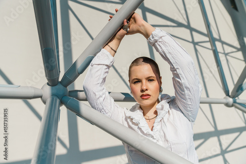 Person in white ruffled shirt posing among metal beams