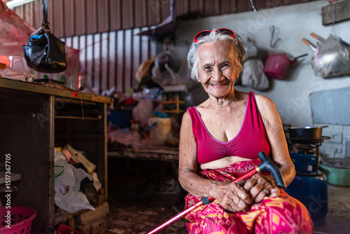 Elderly woman smiling in old home during hot day in Thailand